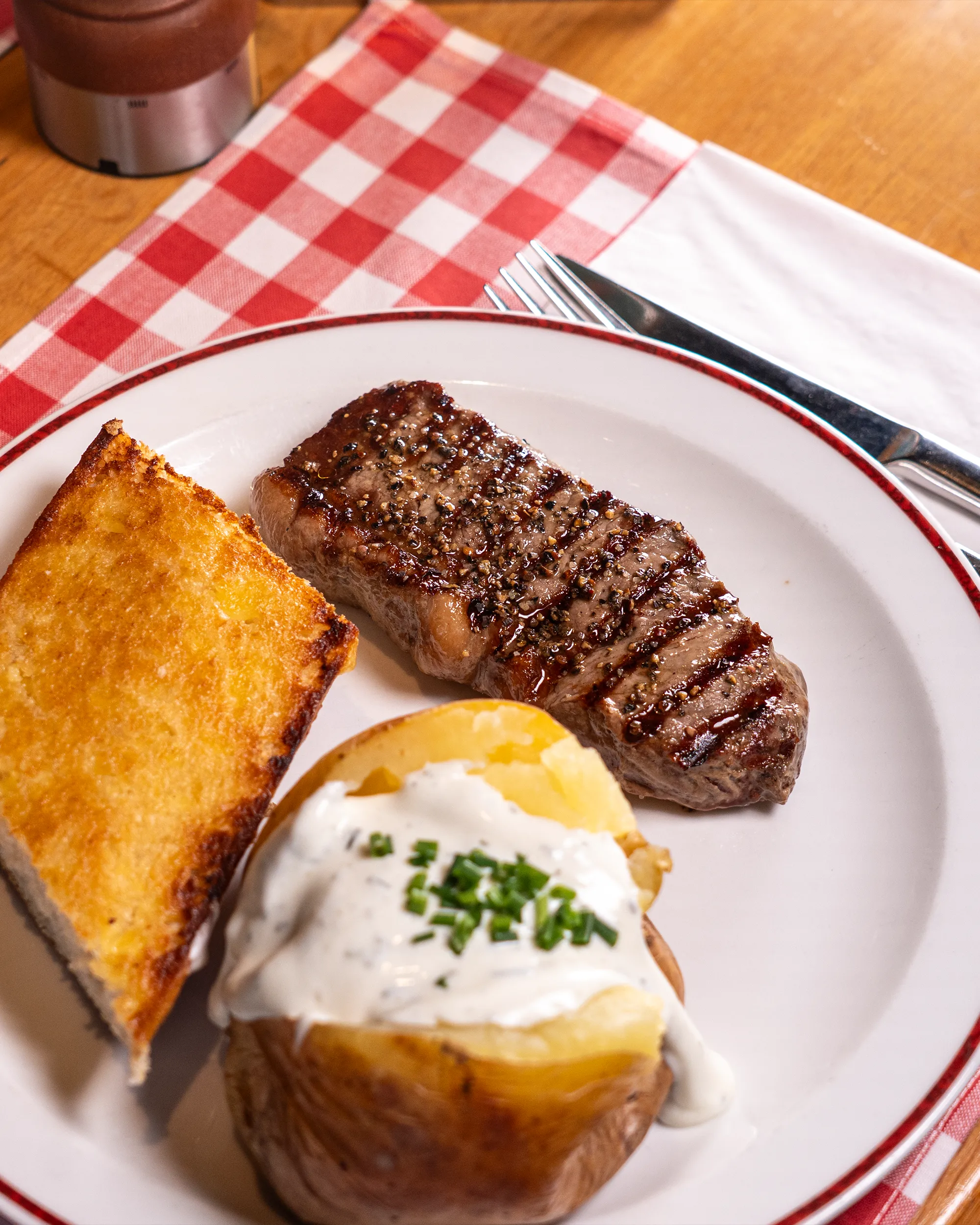 Gegrilltes Steak mit Knoblauchbrot und Ofenkartoffel – Food-Fotografie von Eura Media Wien
